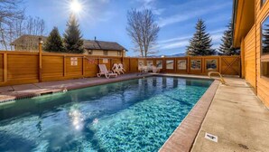A swimming pool with clear water, surrounded by wooden fences and trees.