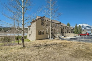 A two-story house with a wooden exterior, a driveway, and a red car parked in front.