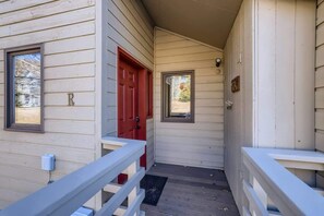 Une maison en bois avec une porte rouge, un petit porche et une boîte aux lettres.