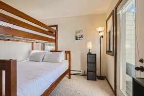 A bedroom with a wooden bed, a nightstand, a lamp, and a framed picture on the wall.