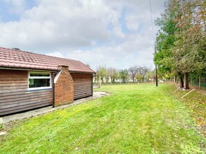 Une maison avec un toit recouvert de tuiles rouges, une cheminée en briques et une petite fenêtre.
