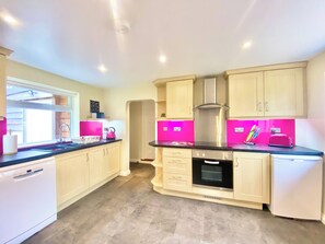 A modern kitchen with light-colored cabinets, a black countertop, and pink accents.