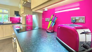 A modern kitchen with a black countertop, a pink wall, and a red toaster. - 2 bedroom accommodation in Winchester (Winchester)