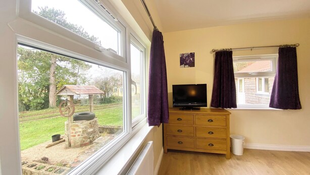 A room with a large window, a wooden dresser, a television, and a purple rug. - 2 bedroom accommodation in Winchester (Winchester)