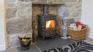 A stone fireplace with a wood-burning stove, a decorative bowl, and a wicker basket.