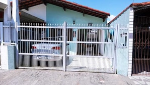 A gated property with a parked car, a blue building, and a red-tiled roof. - Vacation Home in Praia Grande - 3 min. Beach (Praia Grande)