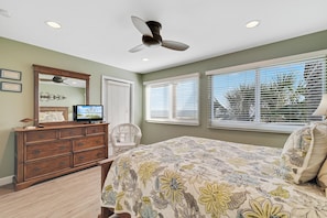 A bedroom with a bed, dresser, television, and ceiling fan. - Needle Rush Point D24 | Beachfront | Walk to FloraBama | 2 Pools | Boat Slips | My Beach Getaways (Pensacola)