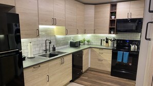Una cocina moderna con armarios de madera, un refrigerador negro, un microondas y una estufa.