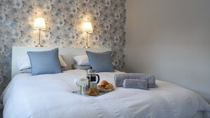 A neatly made bed with white bedding, two bedside lamps, and a tray with croissants and a coffee pot. - 2 bedroom accommodation in York (York)