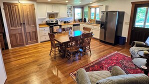 A spacious kitchen with wooden cabinets, a dining table, and chairs. - Historic Log Cabin on 200 acre farm, pasture and forest with panoramic views! (Lebanon)