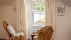 A room with two wicker chairs, a small table, and a window with curtains.