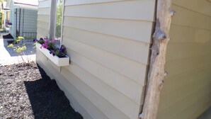 Una casa con macetas de flores moradas, un cartel con el número 7 y un poste de madera.