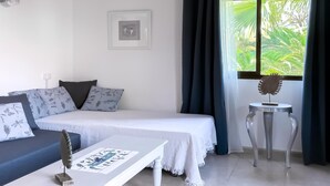 Une chambre à coucher avec un lit, un canapé, une petite table et une fenêtre avec des rideaux.