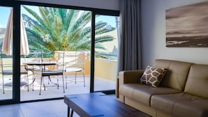 Ein modernes Wohnzimmer mit einer Couch, einem Couchtisch und einem Balkon mit Tisch und Stühlen.