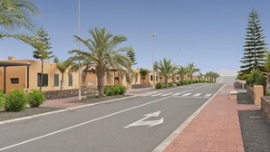 Een straat met palmbomen en gebouwen, onder een heldere lucht.