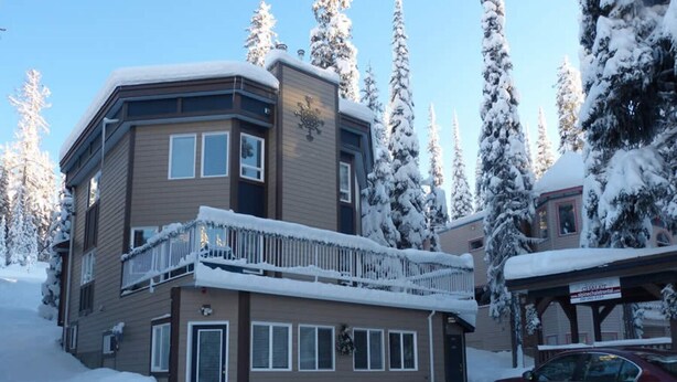 A multi-story building with a balcony, surrounded by snow-covered trees. - Ground Level, 2 Bedroom Suite - Close to Village and The Pond!  (Silver Star Mountain)
