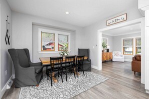 A dining area with a wooden table and chairs, a patterned rug, and a view of the outside through large windows. - Best Location, Renovated, Walk Uptown! - 3br/3ba (Perrysburg)