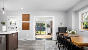 A modern kitchen with a wooden island, a dining area with a round table, and a view of the backyard through glass doors. - Best Location, Renovated, Walk Uptown! - 3br/3ba (Perrysburg)