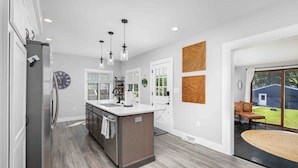 A modern kitchen with a central island, pendant lighting, and a view of the backyard through large windows. - Best Location, Renovated, Walk Uptown! - 3br/3ba (Perrysburg)