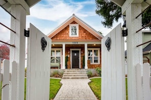 A house with a number '1209' on the front door, a wooden facade, and a brick pathway leading to the entrance. - Luxury Historic Cottage w/ Chef's Kitchen Downtown (Coeur d'Alene)