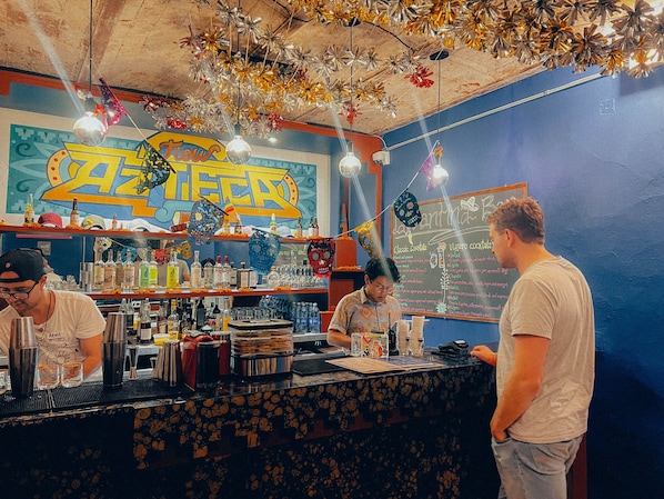 A bar with a counter, shelves with bottles, and a chalkboard menu.