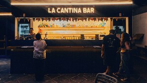 Un bar llamado 'La Cantina Bar', con una barra que muestra diferentes botellas y vasos.