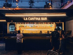 Een bar genaamd 'La Cantina Bar' met een toonbank waarop verschillende flessen en glazen staan.