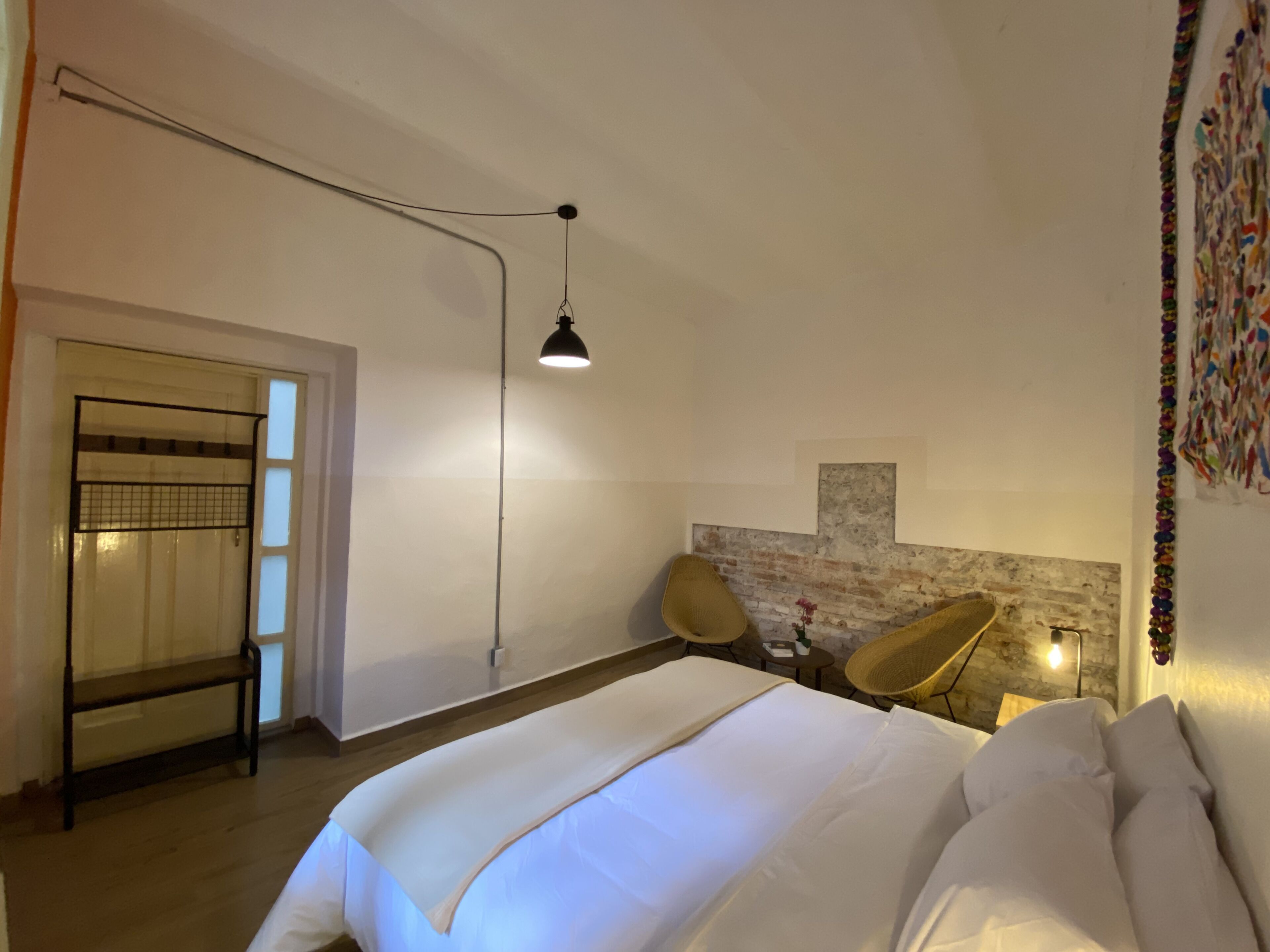 Un dormitorio con cama, una silla, un escritorio e iluminación empotrada en la pared.