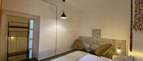 Un dormitorio con cama, una silla, un escritorio e iluminación empotrada en la pared.