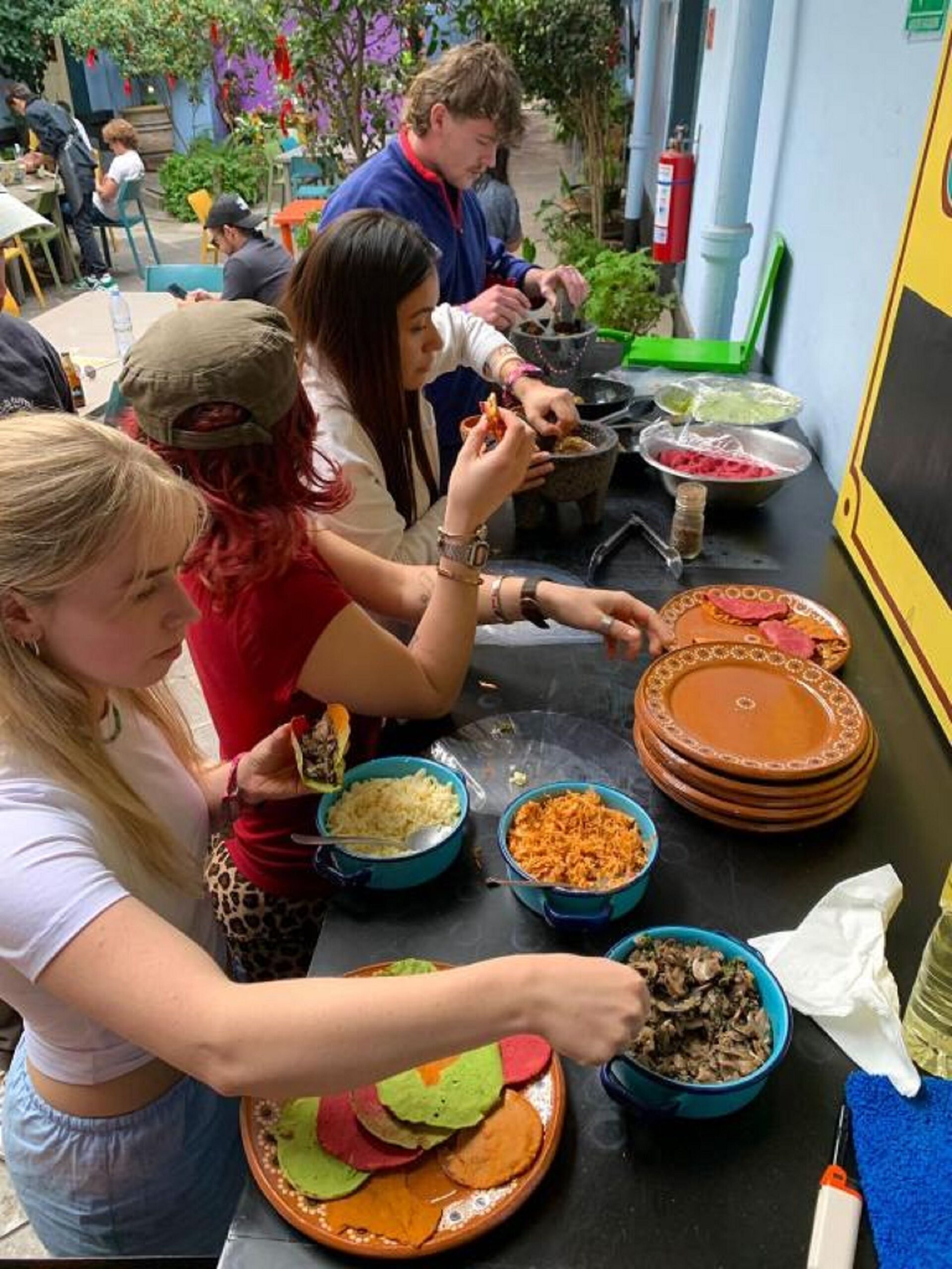 A group of people dining outdoors with various dishes on a table.