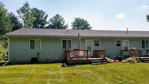 A single-story house with a front porch, a small deck, and a well-maintained lawn.