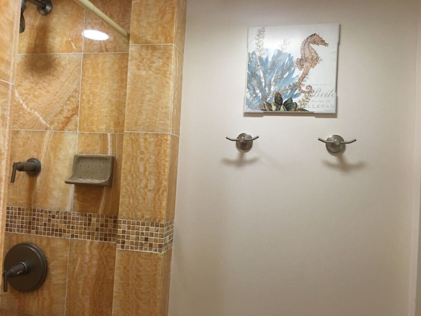 A bathroom with a shower, a towel rack, and a framed artwork on the wall.