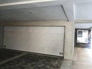 A spacious garage with a large white door, a tiled floor, and a stone accent wall with a window.