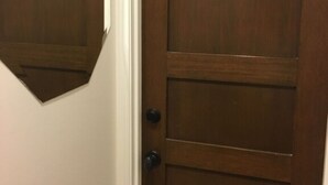 Une porte en bois, dotée d’une poignée et d’un trou de serrure, qui donne probablement sur une pièce ou un couloir.