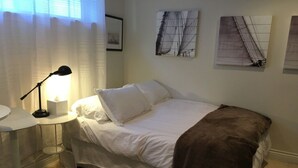 Une chambre à coucher avec un lit, une table de chevet avec une lampe, une petite table ronde et un tapis en peau de vache.