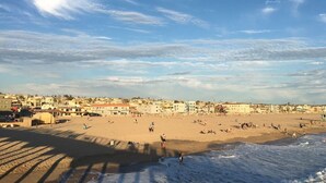 Un paysage urbain côtier avec une plage, des bâtiments et un ciel dégagé.