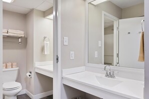 A bathroom with a white sink, mirror, and toilet. - Top Floor Standard Suite Bay View (North East)