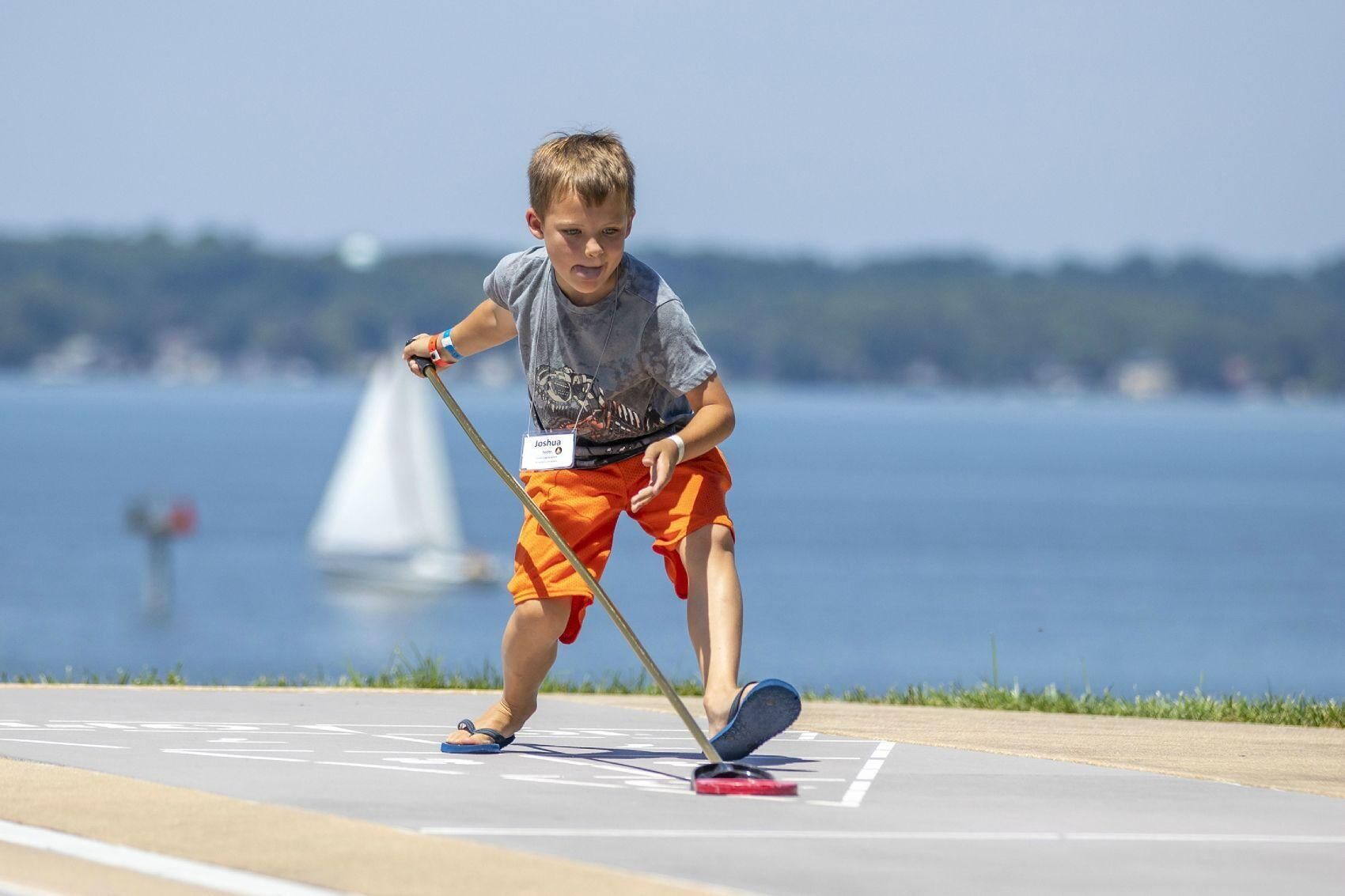 A child playing shuffleboard on a sunny day.