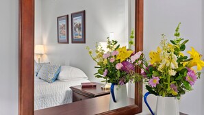 A hotel room with a bed, a nightstand, a lamp, and two framed pictures on the wall. - Second Floor East Standard Suite (North East)