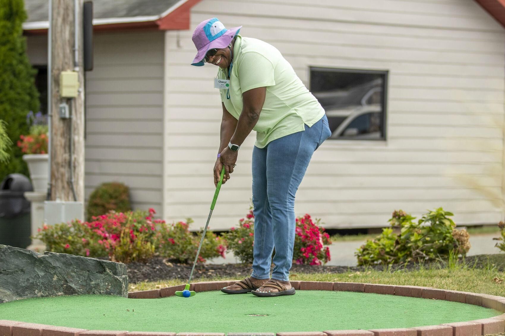 Iemand speelt minigolf in een achtertuin, met een huis op de achtergrond.