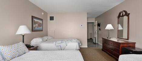 A hotel room with two beds, a dresser, a mirror, and a lamp.