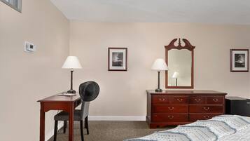 A bedroom with a bed, a desk, a chair, a dresser, and two wall-mounted lamps.