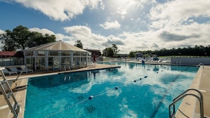 A swimming pool with clear blue water, surrounded by lounge chairs and a covered seating area. - Top Floor Handicap Accessible Bay View (North East)
