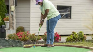 A person playing mini-golf in a backyard with a house in the background.