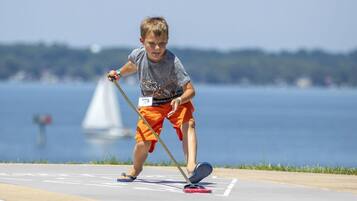 A child playing shuffleboard on a sunny day.