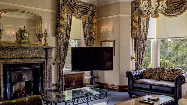 A traditional living room with a fireplace, leather sofa, and a flat-screen TV.