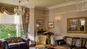 A well-appointed living room with a large window, a chandelier, and classic furniture.