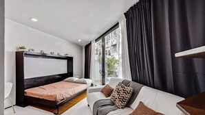 Een moderne slaapkamer met een groot bed, een bank en een raam met gordijnen.