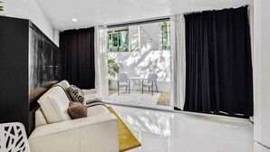 Een moderne woonkamer met een bank, een salontafel en uitzicht op een terras met stoelen en een tafel.