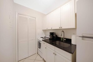 The kitchen has a fridge, stove with oven, and  microwave